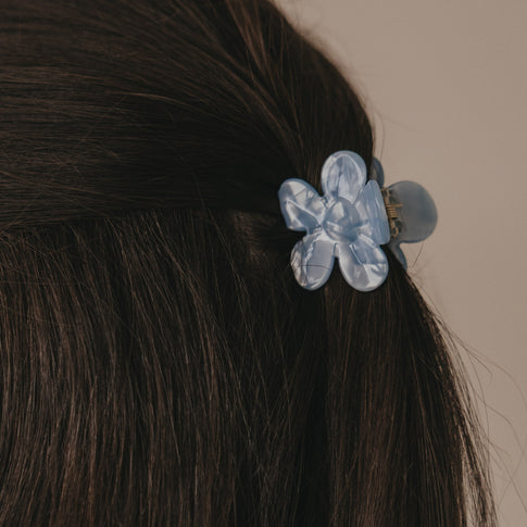 Detail Haarspange Blume hellblau im braunen Haar mit glänzender Oberfläche
