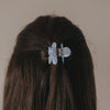 Haarspange Blume hellblau wird von Hand im Haar befestigt