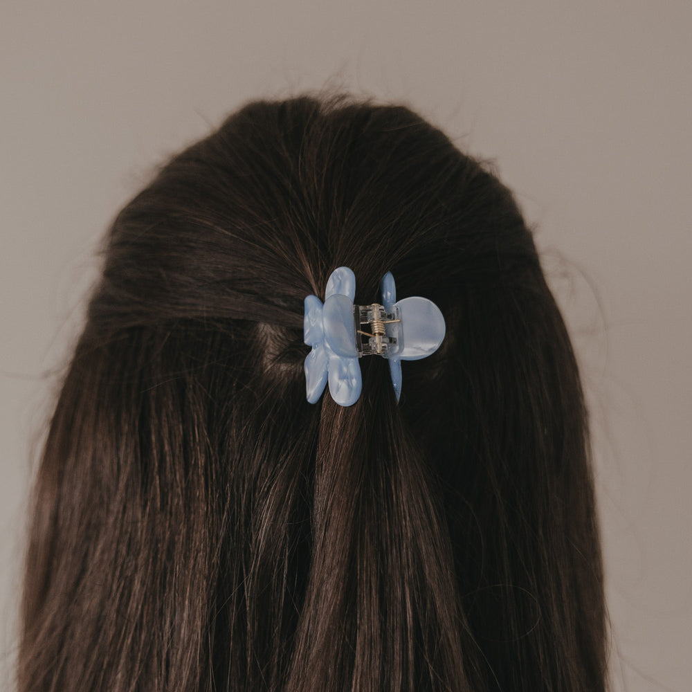 Haarspange Blume hellblau wird von Hand im Haar befestigt