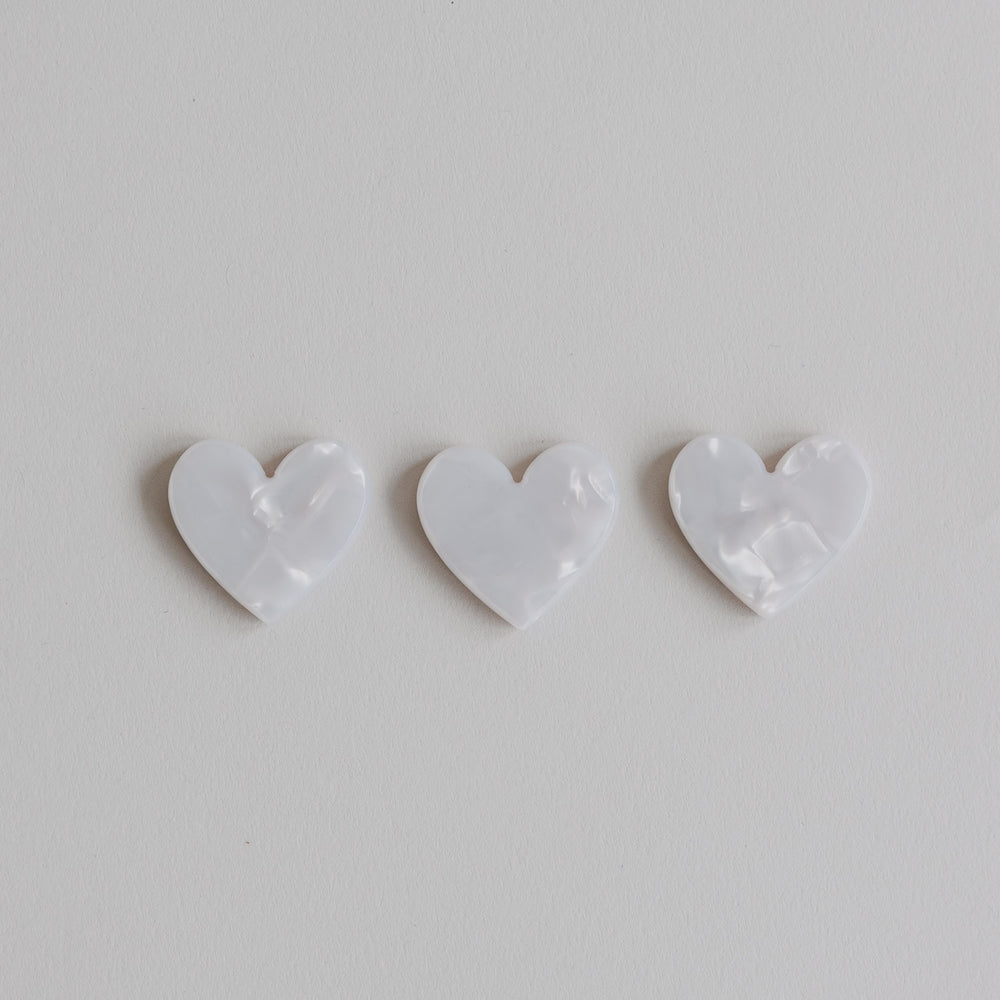 Drei weiße herzförmige Magnete in schimmernder Perlmutt-Optik auf hellem Hintergrund