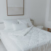 Gemachtes Bett mit 3 Kissen und einer umgeklappten Ecke der Decke und kleinen schwarzen gedruckten Herzen.