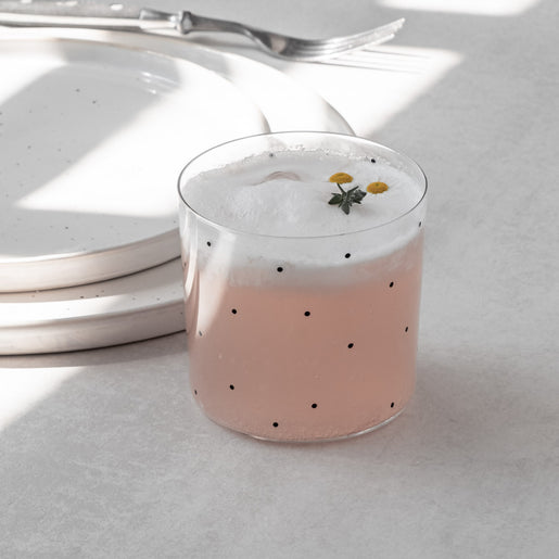 Glas mit schwarzen Punkten und rosa Getränk mit Schaum, stilvolles Trinkglas modern und minimalistisch