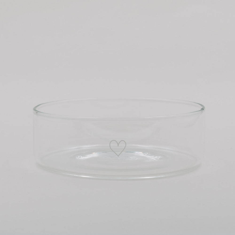 Transparente Glas-Schale mit zartem Herzmotiv, schlicht und minimalistisch vor hellem Hintergrund.