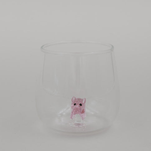 Freigestelltes Trinkglas mit Schwein Figur im Boden, minimalistisches Glasdesign