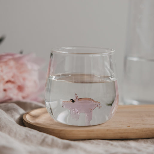 Trinkglas mit Schwein Motiv gefüllt mit Wasser auf Holzbrett, stilvolles Glas