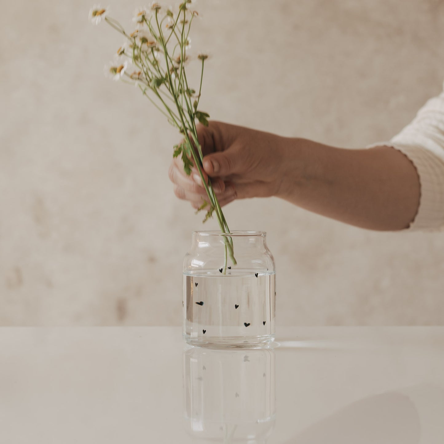 Glasvase mit Herzmuster, dekoriert mit frischen Wiesenblumen