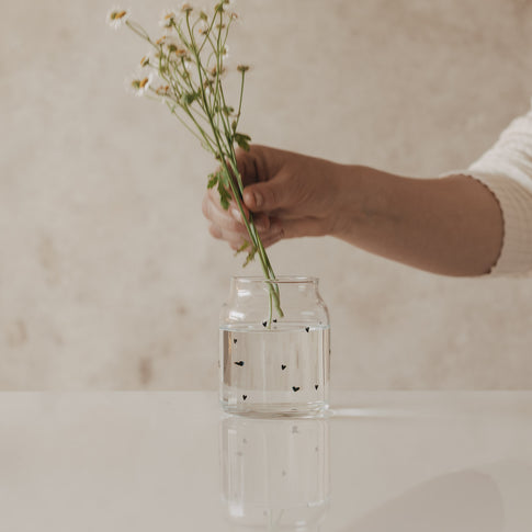 Glasvase mit Herzmuster, dekoriert mit frischen Wiesenblumen