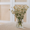 Glasvase mit Herzmuster als Deko mit Blumen auf hellem Tisch