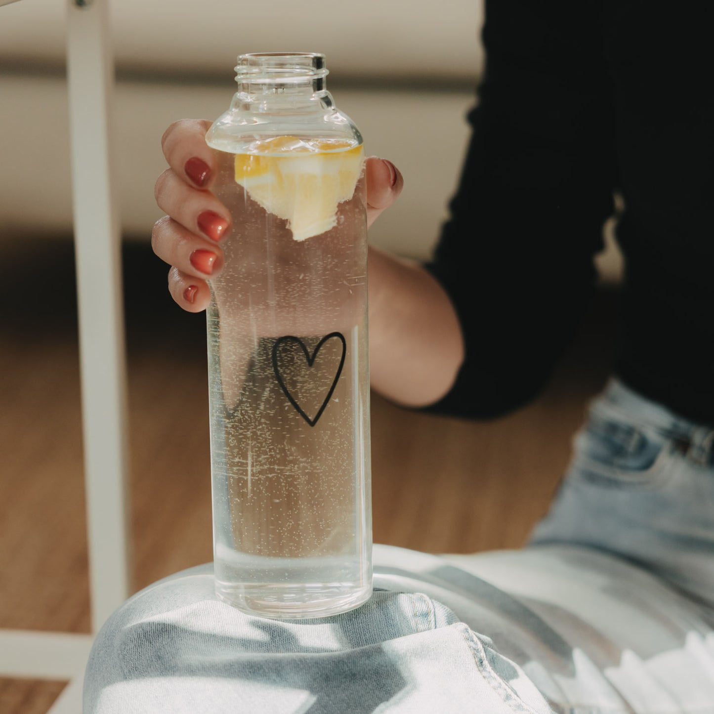 Glas Trinkflasche Herz 750 ml in der Hand, gefüllt mit sprudelndem Zitronenwasser