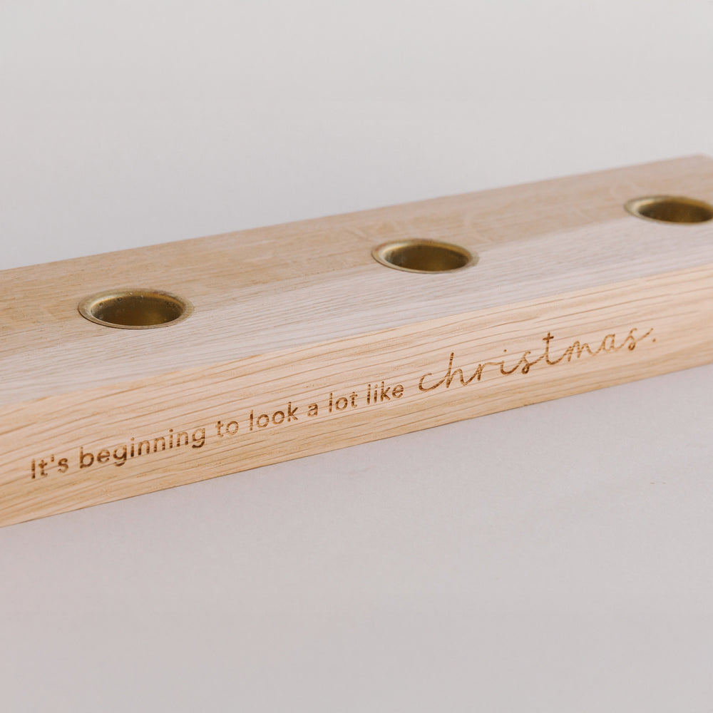 Nahaufnahme Holzkerzenbrett mit Kerzenplätzen und Gravur Christmas