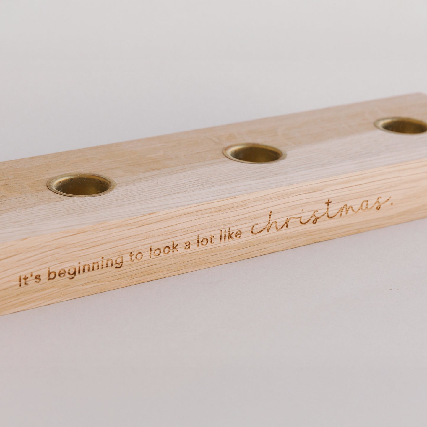 Nahaufnahme Holzkerzenbrett mit Kerzenplätzen und Gravur Christmas