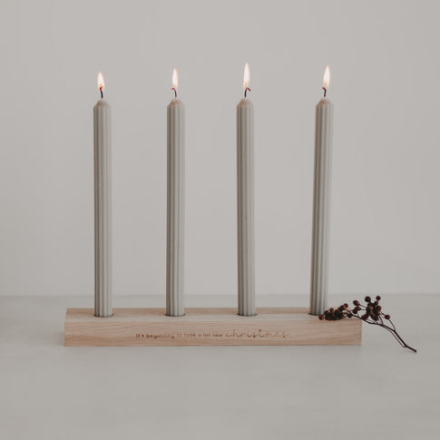 Adventskerzenbrett mit vier brennenden Kerzen und Gravur Christmas auf hellem Holz
