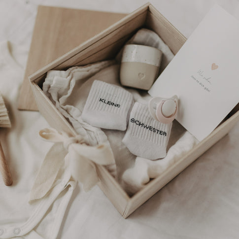 Detailaufnahme der geöffneten Erinnerungsbox Herz mit Babysöckchen, Schnuller und Karte.