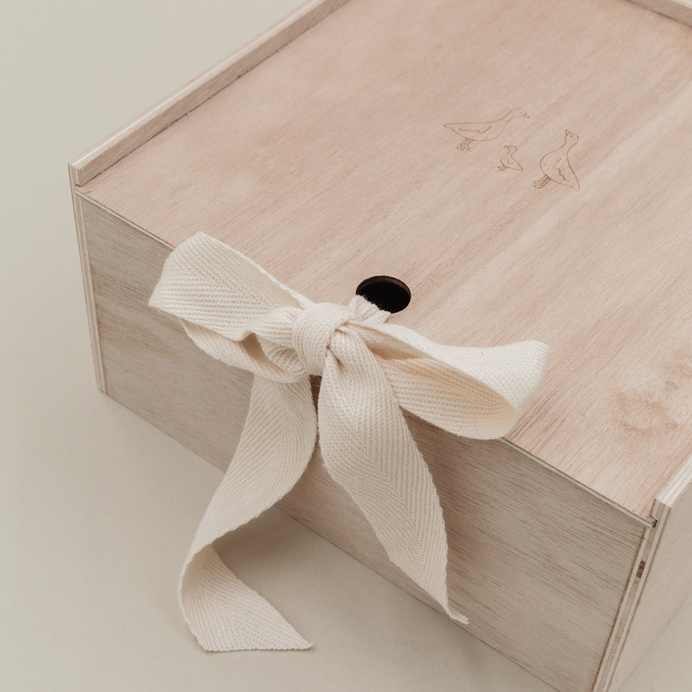 Detailfoto des Schleifenbands an der Holz-Erinnerungsbox mit feiner Gänsegravur auf dem Deckel.