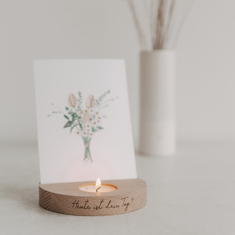 Holz-Teelicht-Kartenhalter „Heute ist dein Tag“ mit brennendem Teelicht und Blumenkarte in heller Umgebung.