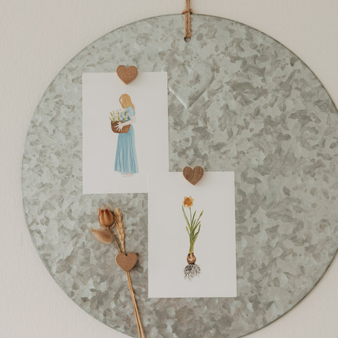 Herzmagnete aus Holz befestigen Karten und Trockenblumen an einer runden Magnettafel