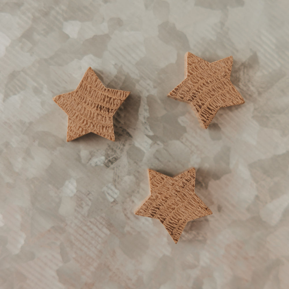 Drei Sternmagnete aus Holz mit individueller Maserung auf einer Magnettafel