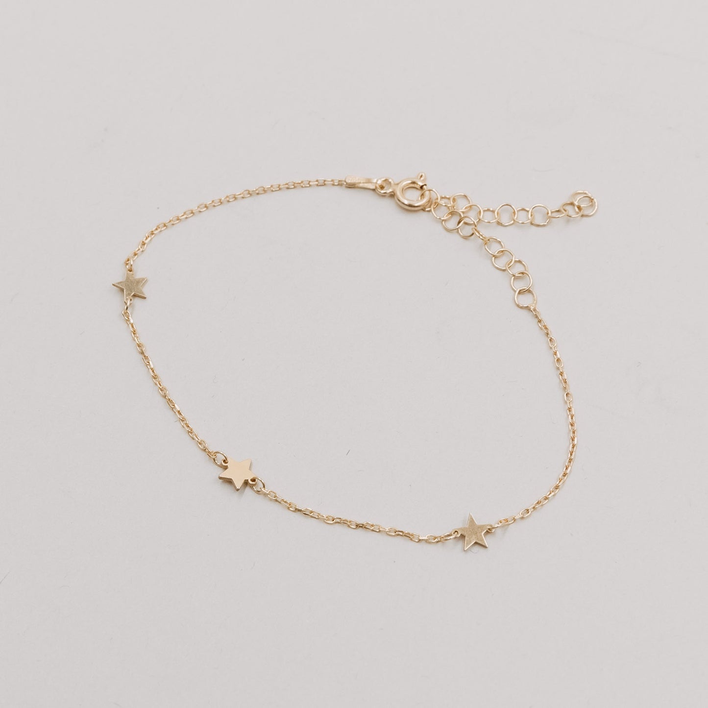 Produktbild des Armbands Jackie Gold flach liegend mit fünf kleinen Sternanhängern und verstellbarem Verschluss.
