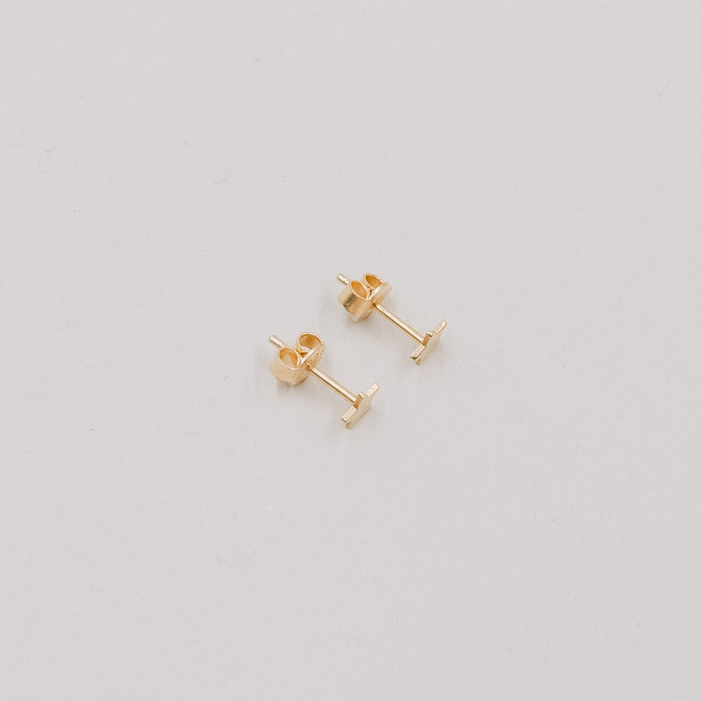 Paar goldene Stern-Ohrstecker Jackie Gold auf hellem Hintergrund, minimalistisches Schmuckdesign.