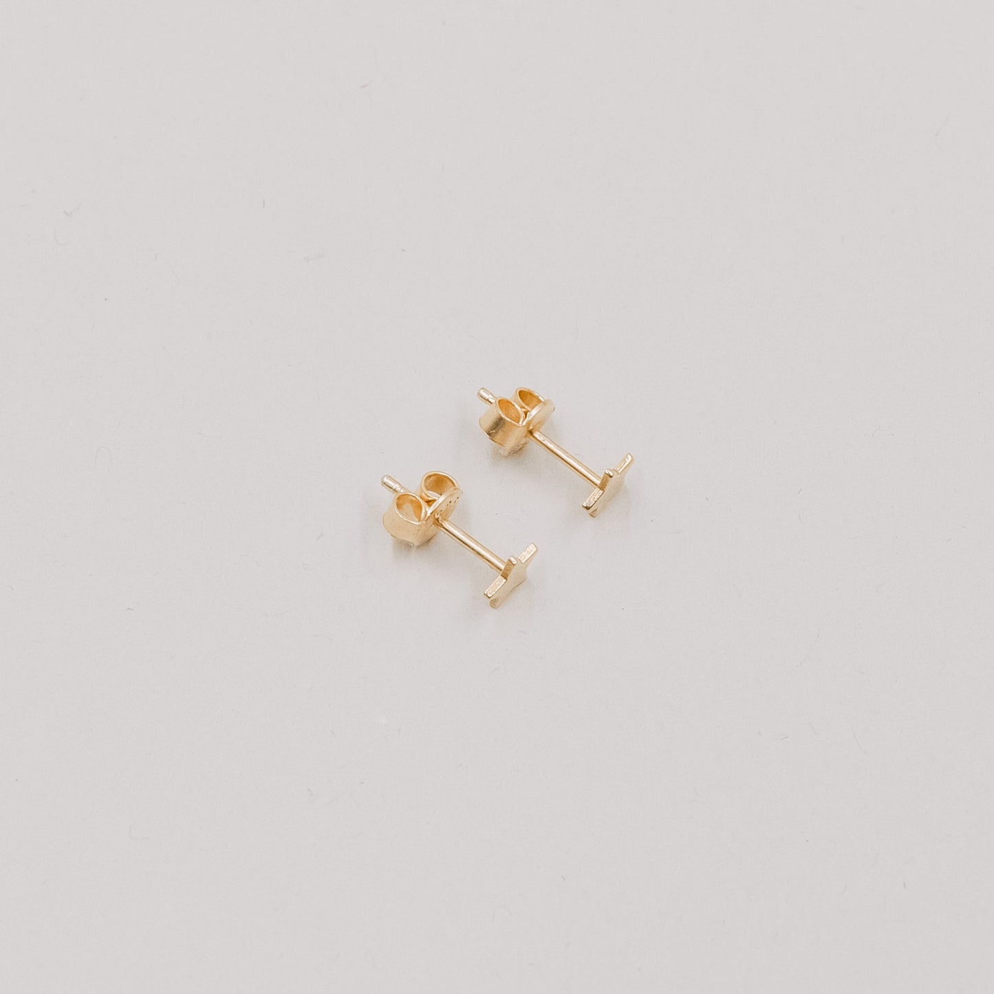 Paar goldene Stern-Ohrstecker Jackie Gold auf hellem Hintergrund, minimalistisches Schmuckdesign.