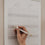 Familienkalender 2026 mit Monatsübersicht Juli, Hand trägt Eintrag mit Stift in Spaltenlayout unter Möwen-Illustration ein.