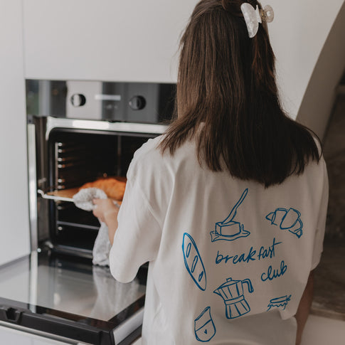 Rückansicht mit Frühstücksillustrationen und „breakfast club“-Aufdruck auf weißem Shirt.