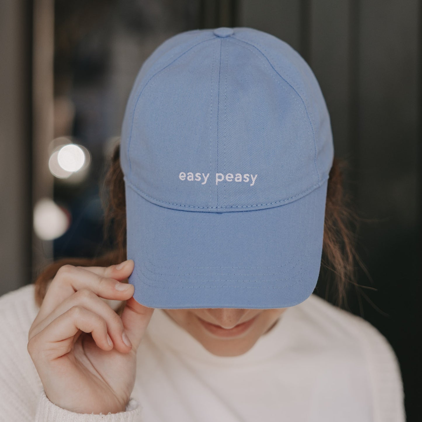 Hellblaue Cap mit Schriftzug „easy peasy“, getragen von Frau
