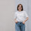 Frau im weißen T-Shirt mit kleinem Herzprint, lässiger Look vor neutralem Hintergrund