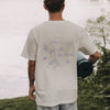 Person von hinten mit Yogamatte, weißes T-Shirt „go with the flow“ mit großem Rückendruck