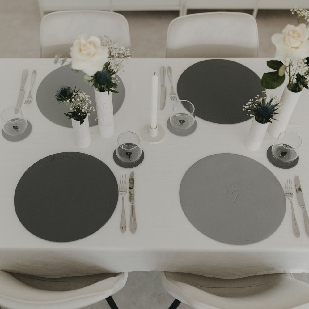 Elegant gedeckter Tisch mit wendbaren runden Platzsets in Grau und Herzprägung für eine stilvolle Tischdeko.