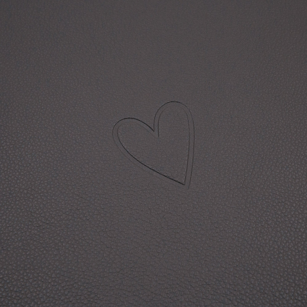 Dunkelgraue Platzset-Oberfläche mit eingeprägtem Herzmotiv in Nahaufnahme.