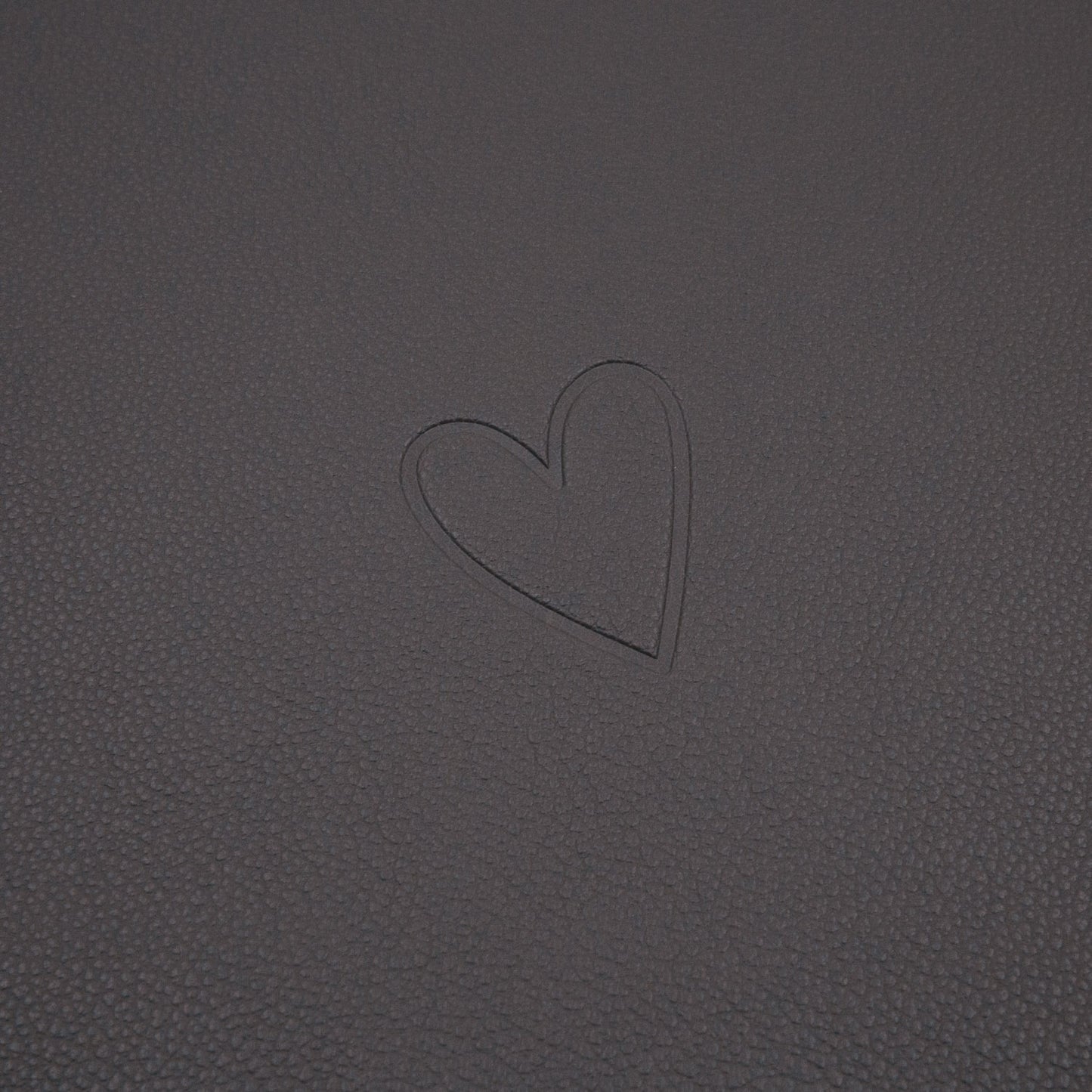 Dunkelgraue Platzset-Oberfläche mit eingeprägtem Herzmotiv in Nahaufnahme.