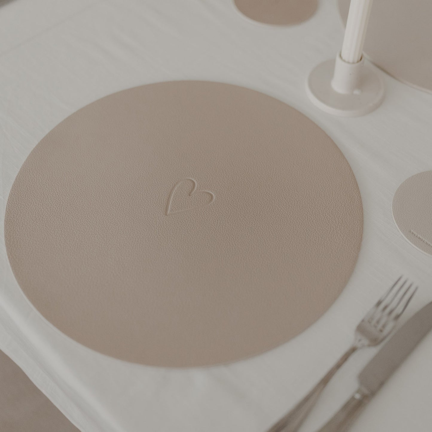 Rundes Platzset in warmem Beige mit geprägtem Herzmotiv als stilvolle Tischdekoration.“