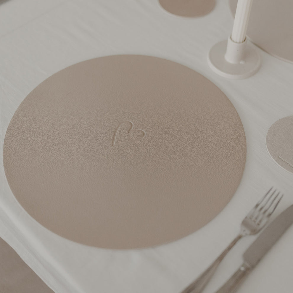 Rundes Platzset in warmem Beige mit geprägtem Herzmotiv als stilvolle Tischdekoration.“