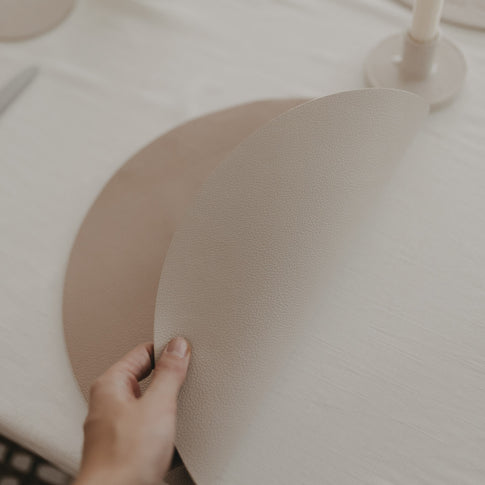 Wendbares Platzset in Beige beim Anheben gezeigt, strukturierte Oberfläche sichtbar.