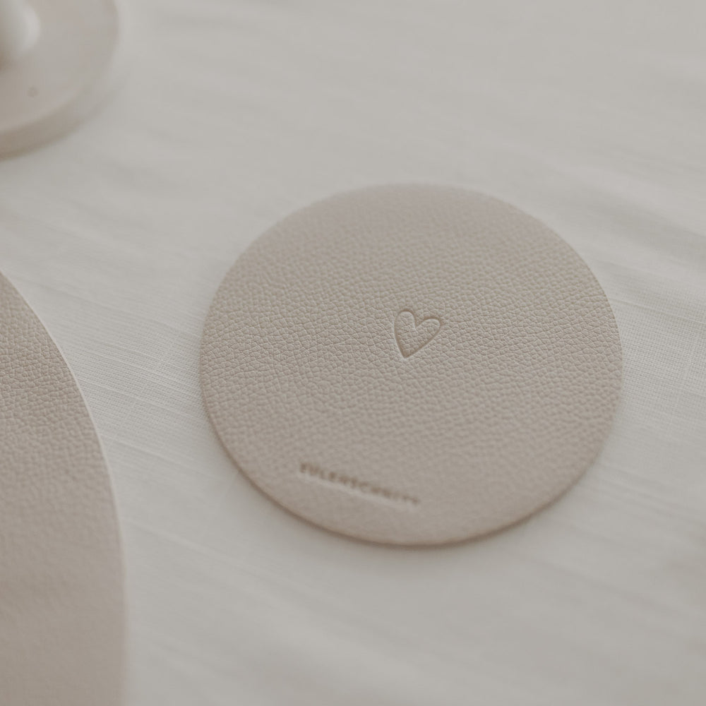 Runder Untersetzer in Creme mit Herzmotiv von Eulenschnitt, dekoriert auf weißem Tisch.