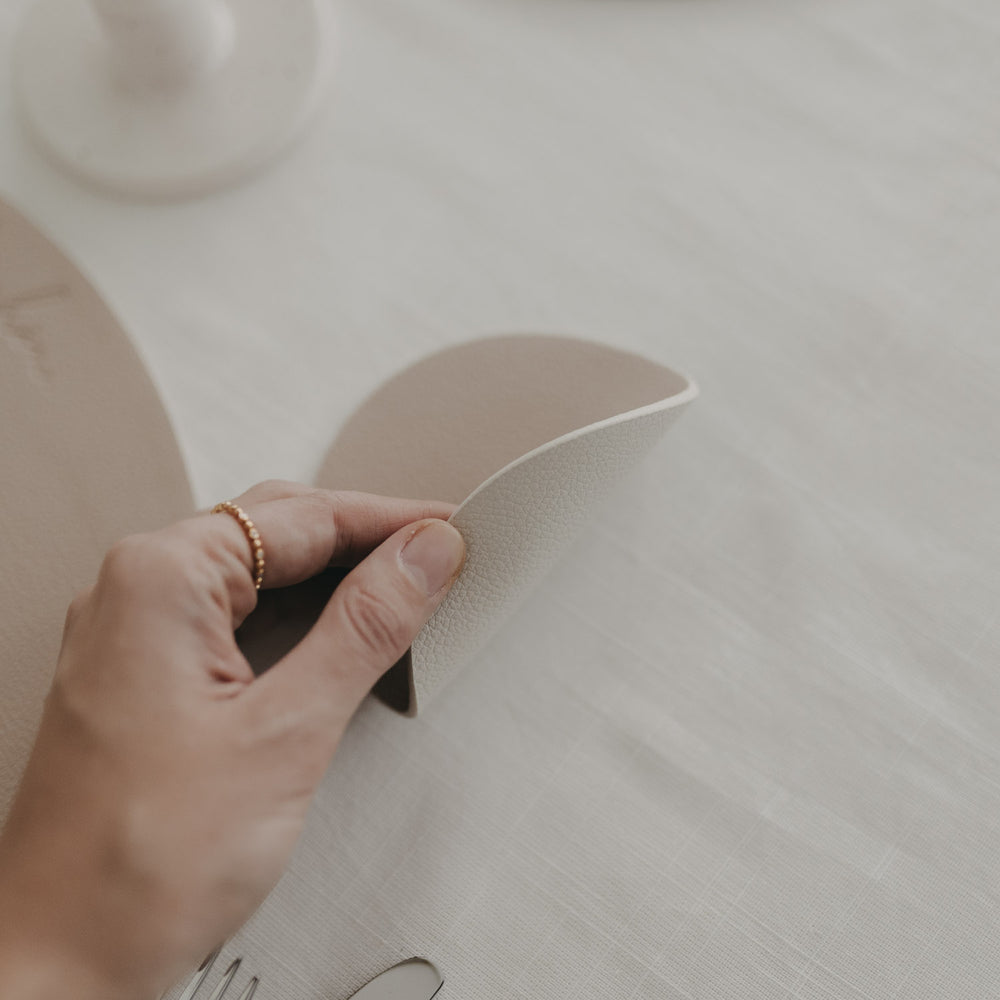 Detailansicht eines cremefarbenen, wendbaren Untersetzers mit Herzprägung und feiner Struktur.