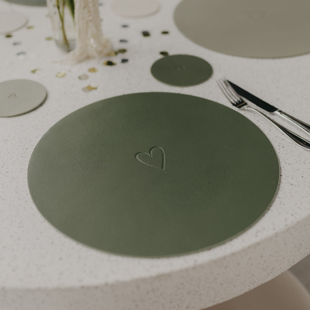Wendbares Platzset Herz Grün in Dunkelgrün auf gedecktem Tisch mit eingeprägtem Herzmotiv.