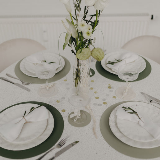 Festlich gedeckter Tisch mit grünen Platzsets und stilvoller Tischdekoration.