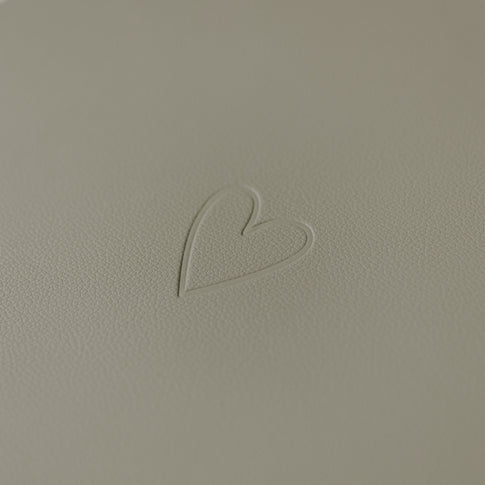 Nahaufnahme des eingeprägten Herzsymbols auf hellem grünen Platzset.