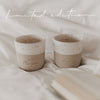 Zwei gesprägte, handgetöpferte Becher stehen auf einem Bett nebeneinander. Einmal mit dem Schriftzug "Guten Morgen" und einmal mit "Lieblingsbecher".