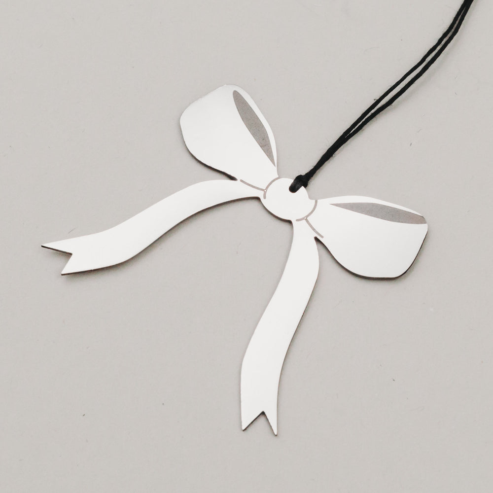 Nahaufnahme des Schleifenanhängers in Silber mit schwarzem Band, auf hellem Hintergrund fotografiert.