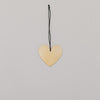 Herzförmiger goldener Metallanhänger mit schwarzem Band auf hellem Untergrund, flach ausgelegt.