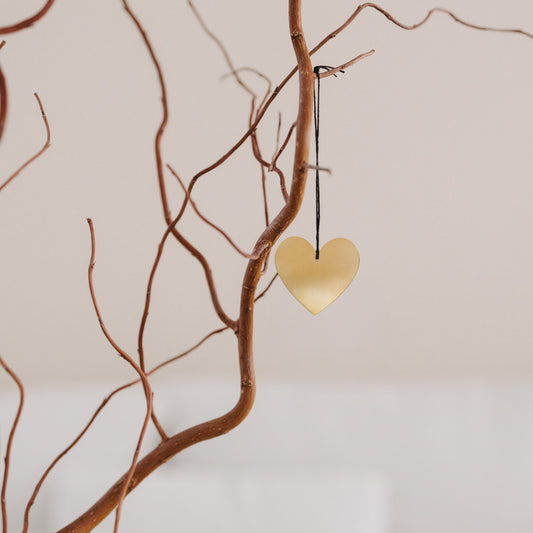 Goldener Herzanhänger aus Metall an Ast, dekoratives Eulenschnitt-Accessoire für natürliche Wohn- und Osterdeko.