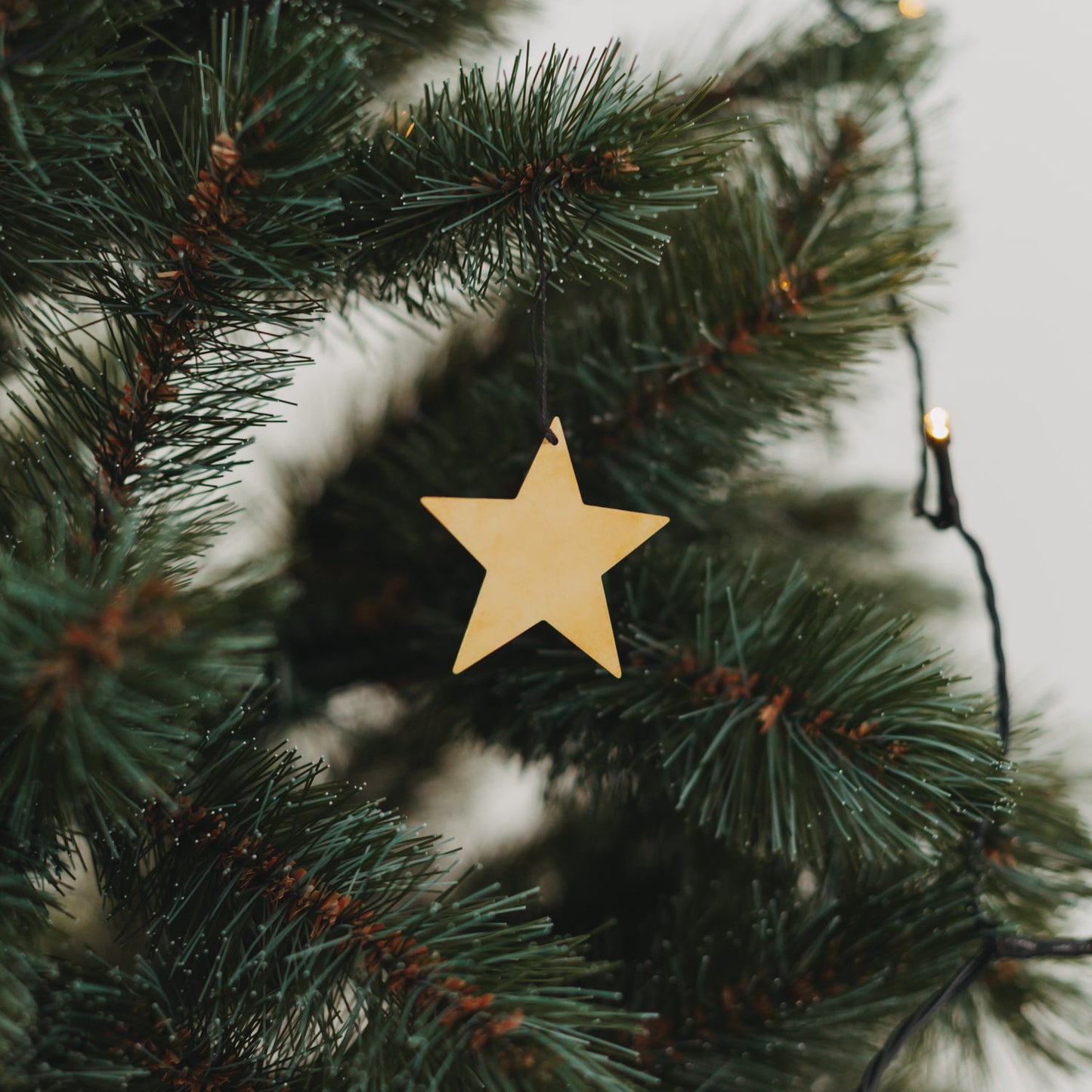 Anhänger Stern aus goldfarbenem Metall am Christbaum – festlicher Baumschmuck für die Weihnachtszeit.