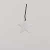 Silberner Sternanhänger aus Metall mit schwarzer Kordel auf hellem Hintergrund, minimalistisch arrangiert.