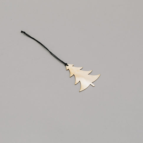 Schlichter goldener Tannenanhänger aus Metall mit schwarzem Band, auf hellem Untergrund liegend.