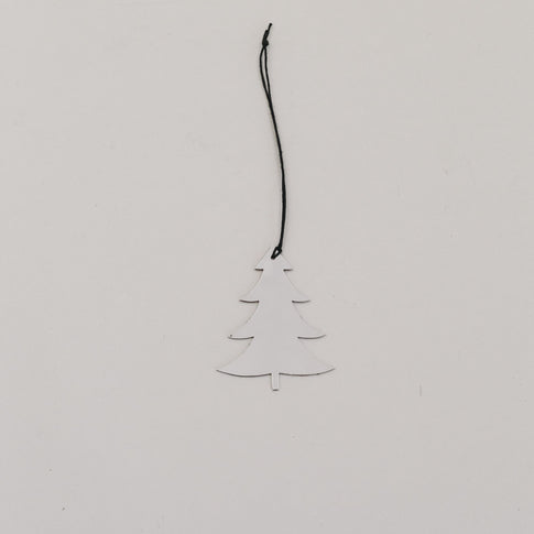 Silberner Tannenanhänger aus Metall mit schwarzer Kordel auf hellem Hintergrund, minimalistisch arrangiert.