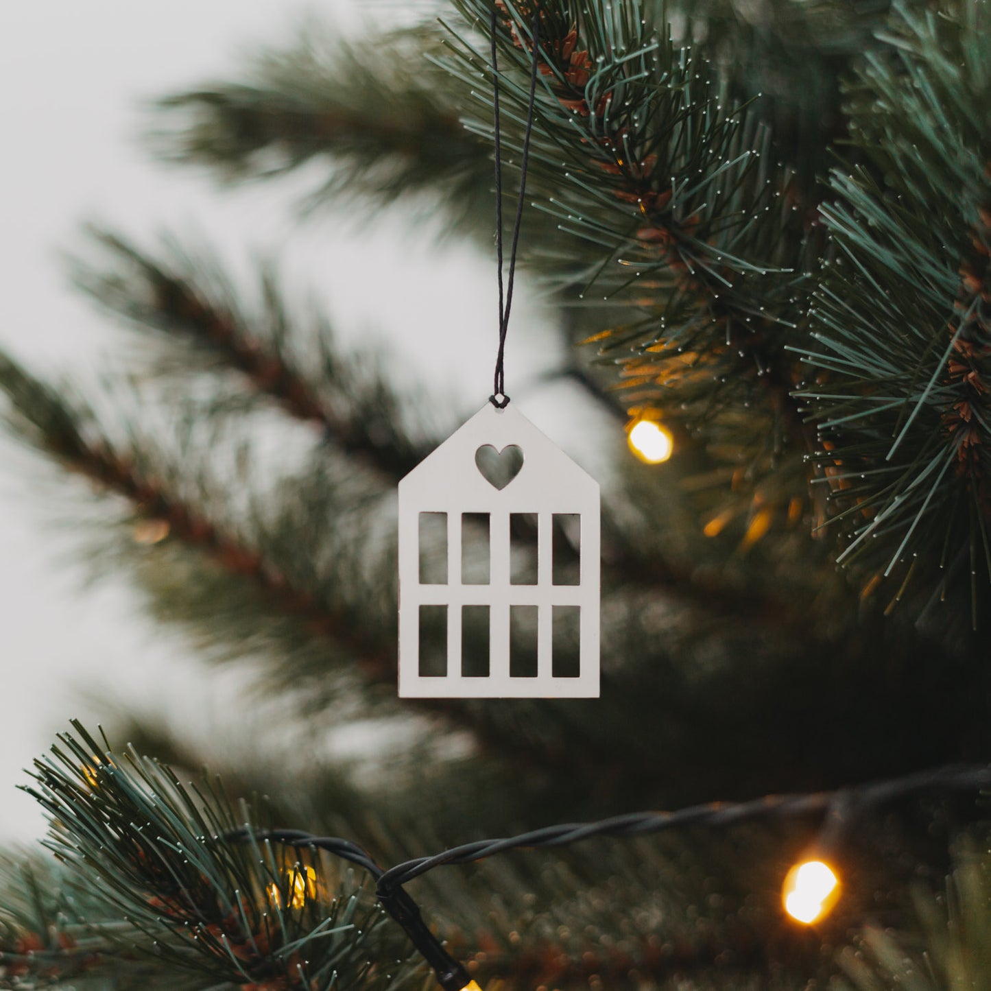 Glänzender silberner Hausanhänger am Weihnachtsbaum.