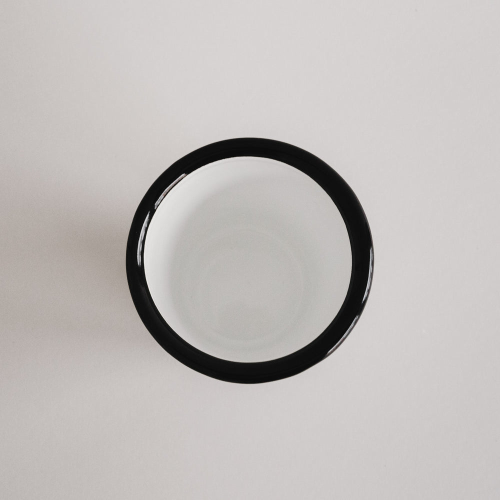 Emaille Tasse Herz von oben fotografiert – schlichtes Off-White Design mit schwarzem Rand.